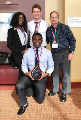 Four member of the SHRM case team stand with their award plaque commemorating their win.